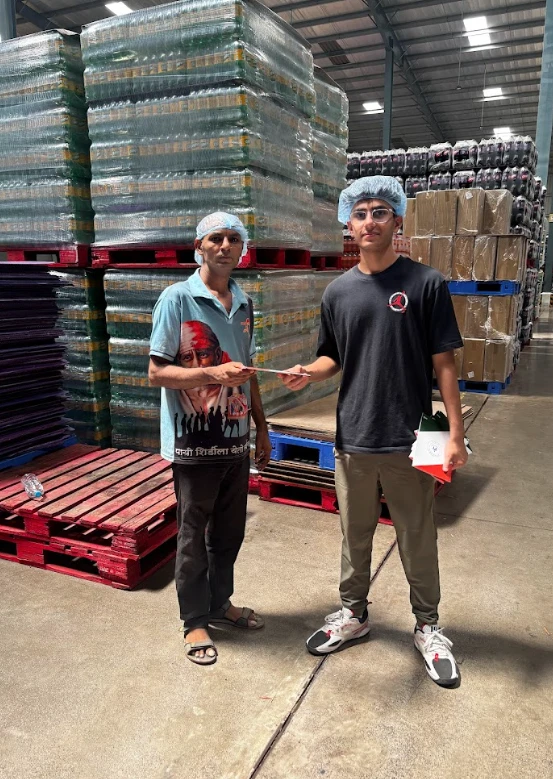 Ayaan Wadhwa handing the booklet to a worker at the warehouse